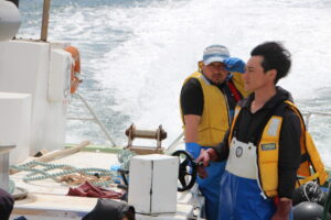 Professional local fishermen expertly navigating their boat and gazing out at the vast ocean, ready to share the profound lessons of the sea in Minamisanriku