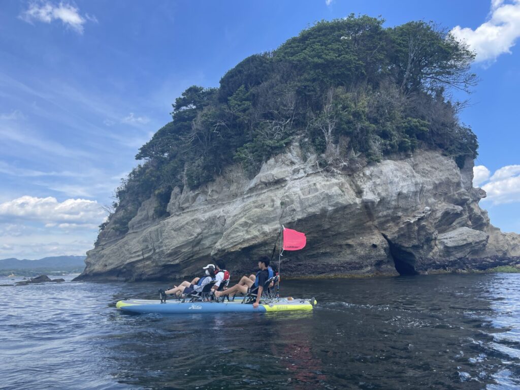 A Hobie kayak swiftly and easily approaching a beautiful lush island within the peaceful Minamisanriku bay