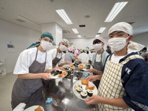 A cheerful group of visitors taking a commemorative photo with their freshly prepared Minamisanriku local cuisine