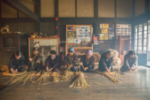 Farmers twisting straw ropes on the earthen floor early in the morning as the first work of the New Year