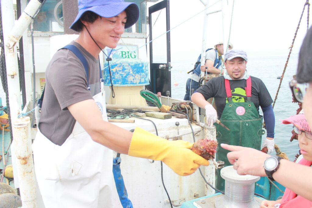 A passionate local fisherman holding a freshly grown sea pineapple to explain the local marine life