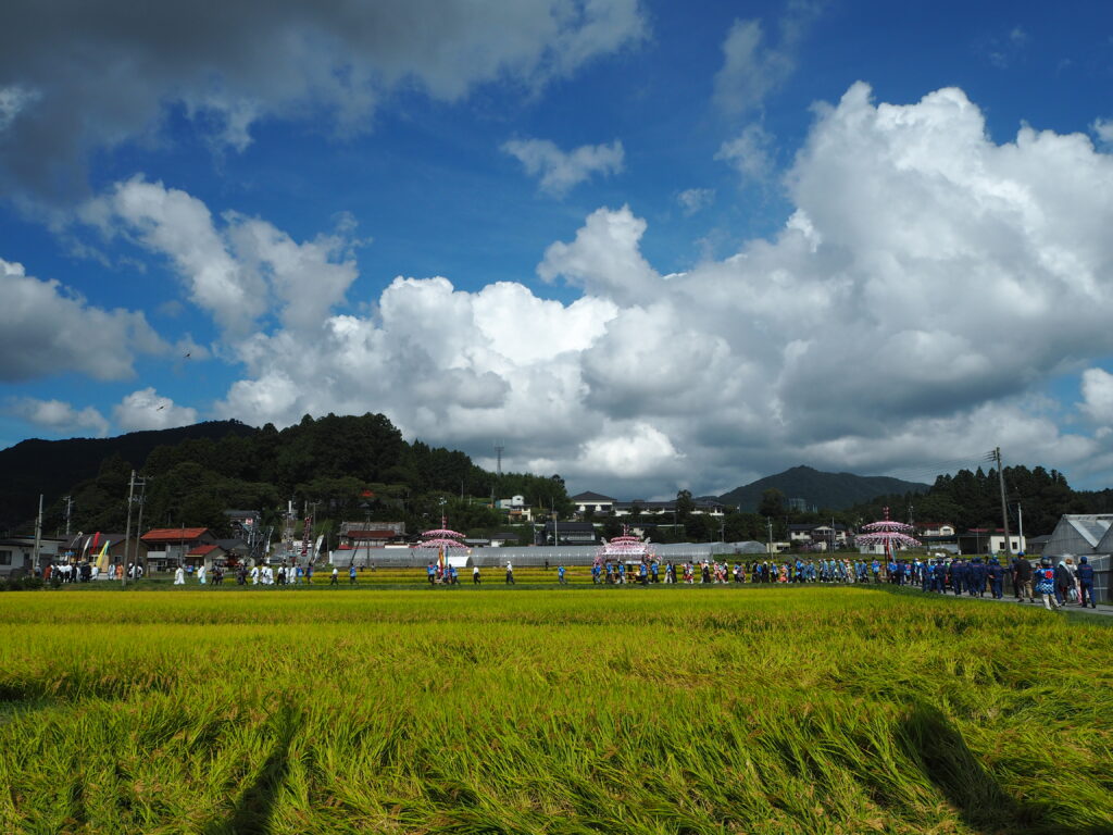 Festive procession and traditional dance celebrating the local harvest at a historic shrine